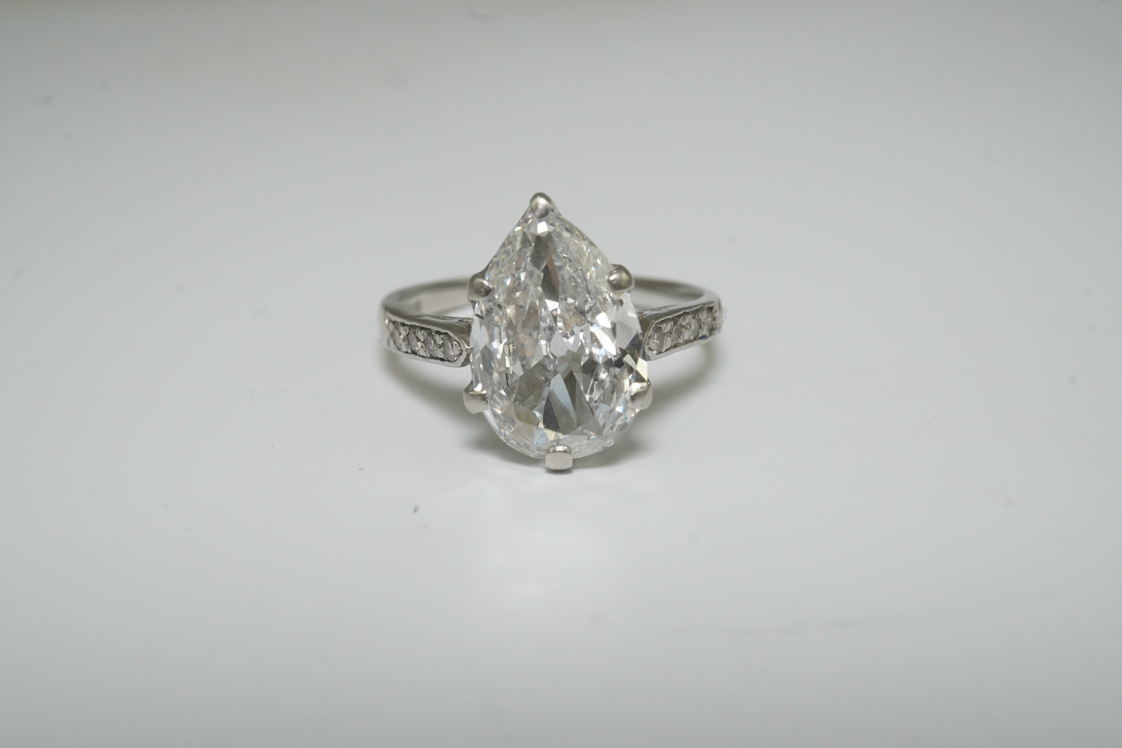 A platinum and pear cut single stone diamond set ring, with diamond set shoulders